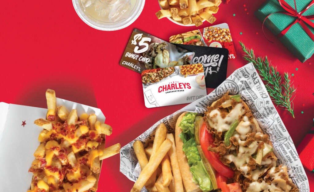 Charleys Cheesesteaks 2022 gift cards and bonus cards on a table with holiday decorations.