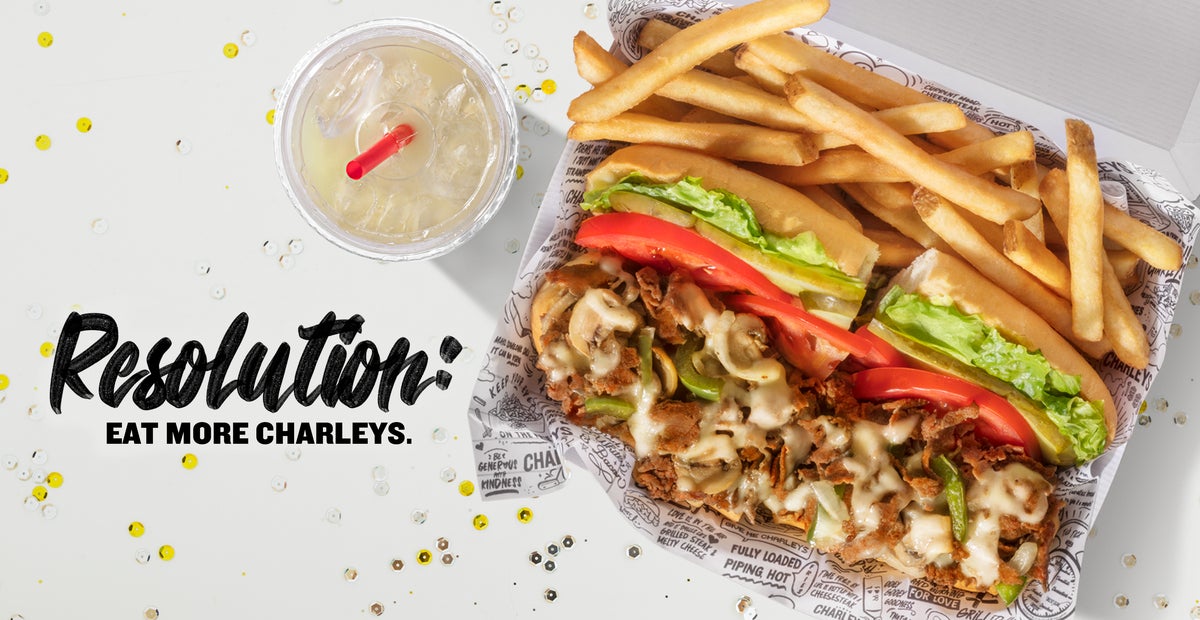 A cheesesteak, fries, and lemonade on a white table with the text "Resolution: Eat More Charleys".