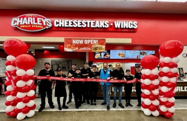 The grand opening ribbon cutting for Charleys Cheesesteaks and Wings in Bonney Lake, WA. This features the team standing in front of the store with a large ribbon and balloon columns.