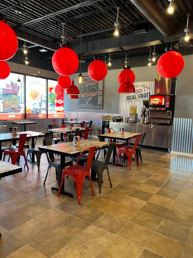 The dining area, including chairs, tables, balloons, at Charleys Cheesesteaks and Wings in Gaithersburg, Maryland. The drink station and front windows are visible in the background.