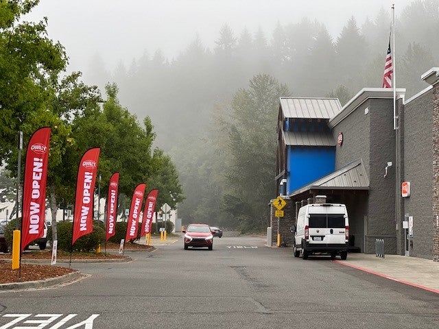 Red "now open!" flags lining the entrance to the Walmart Supercenter in Bonney Lake, WA where Charleys Cheesesteaks and Wings is located.