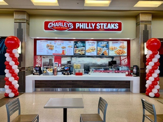 The front counter at Charleys Cheesesteaks in St. Louis Premium Outlets. The table and chairs at the Premium Outlets dining area are visible in the foreground.