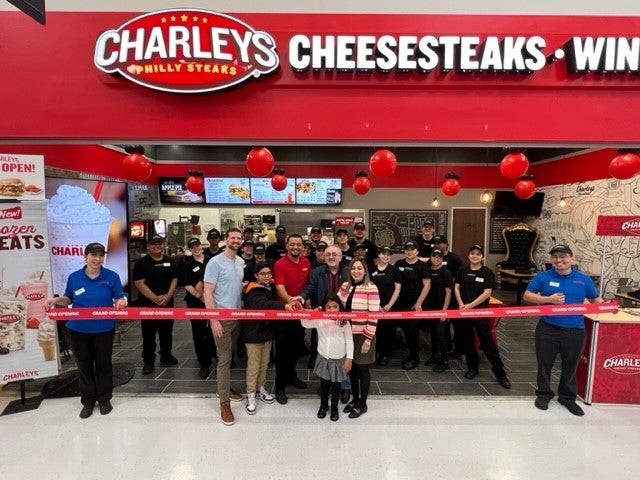 The Charleys Cheesesteaks and Wings team at the grand opening of Charleys at Murrieta Hot Springs Rd. The team is standing in front of the entrance to the store with a red ribbon and balloons.