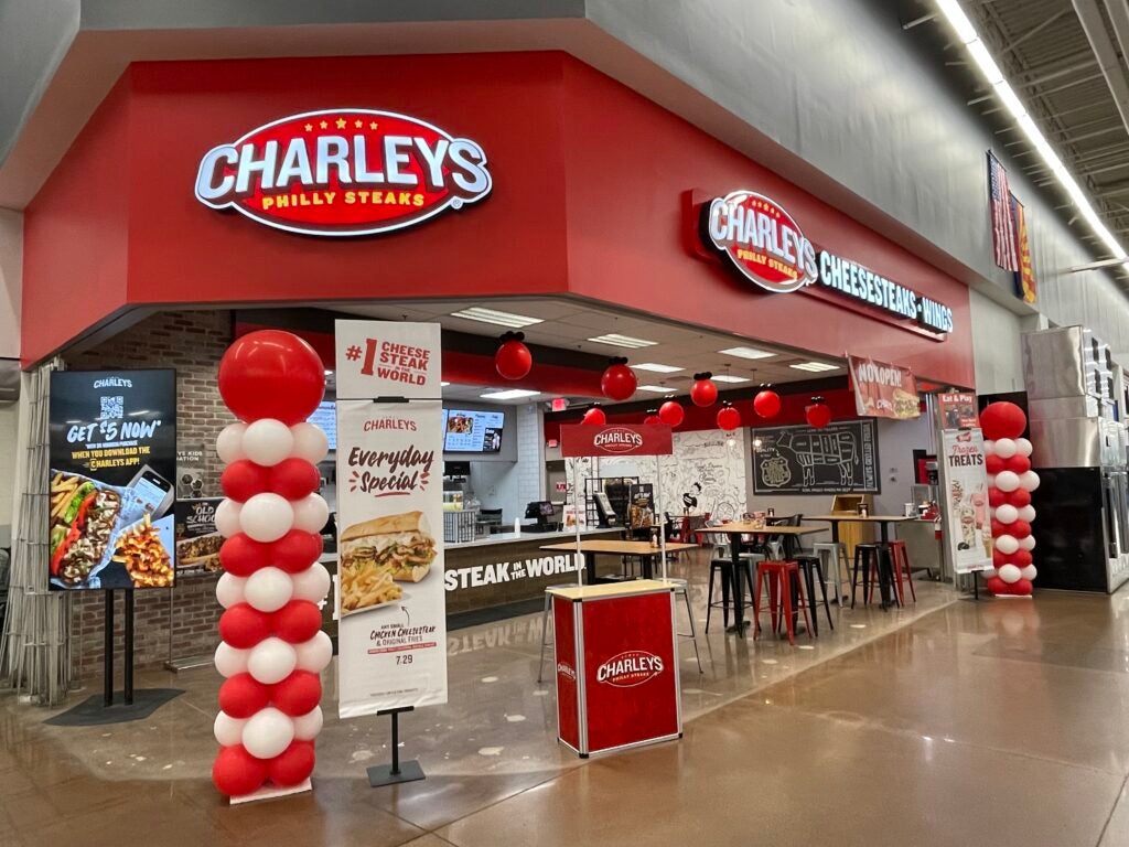 The entrance to Charleys Cheesesteaks and Wings at Walmart - Stockton Hill Rd. during the grand opening in November 2022. In the picture are balloons and signs promoting the restaurant.