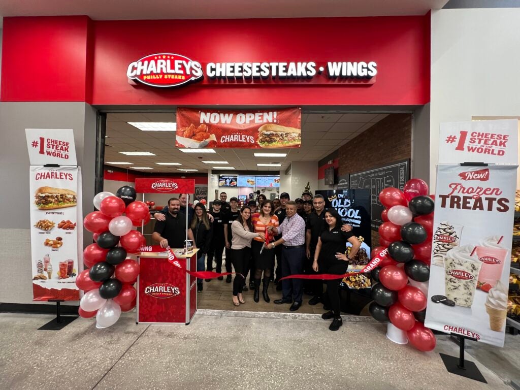 The grand opening ribbon cutting at Charleys Cheesesteaks and Wings at Walmart - 1700 S. Orange Blossom Trail in November 2022. This image features the team at Charleys cutting a ribbon at the entrance of the restaurant.