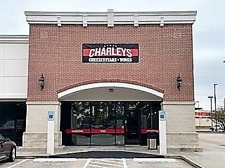 The entrance to Charleys Cheesesteaks and Wings at Spring Town Center. This image features the front doors and exterior sign on a red brick building.
