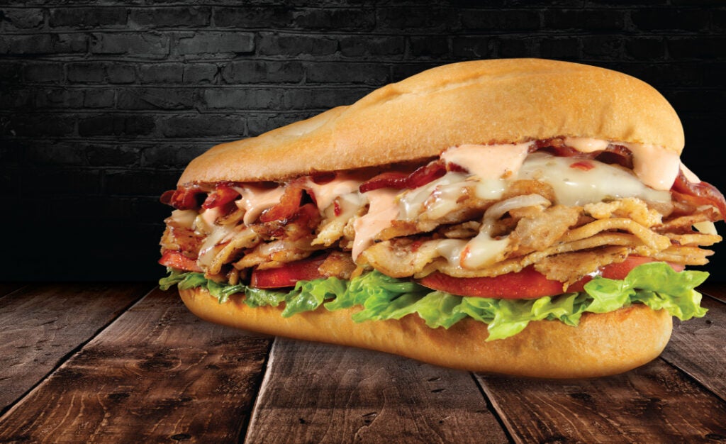 The Bacon Chipotle Cheesesteak from Charleys on a wooden table.