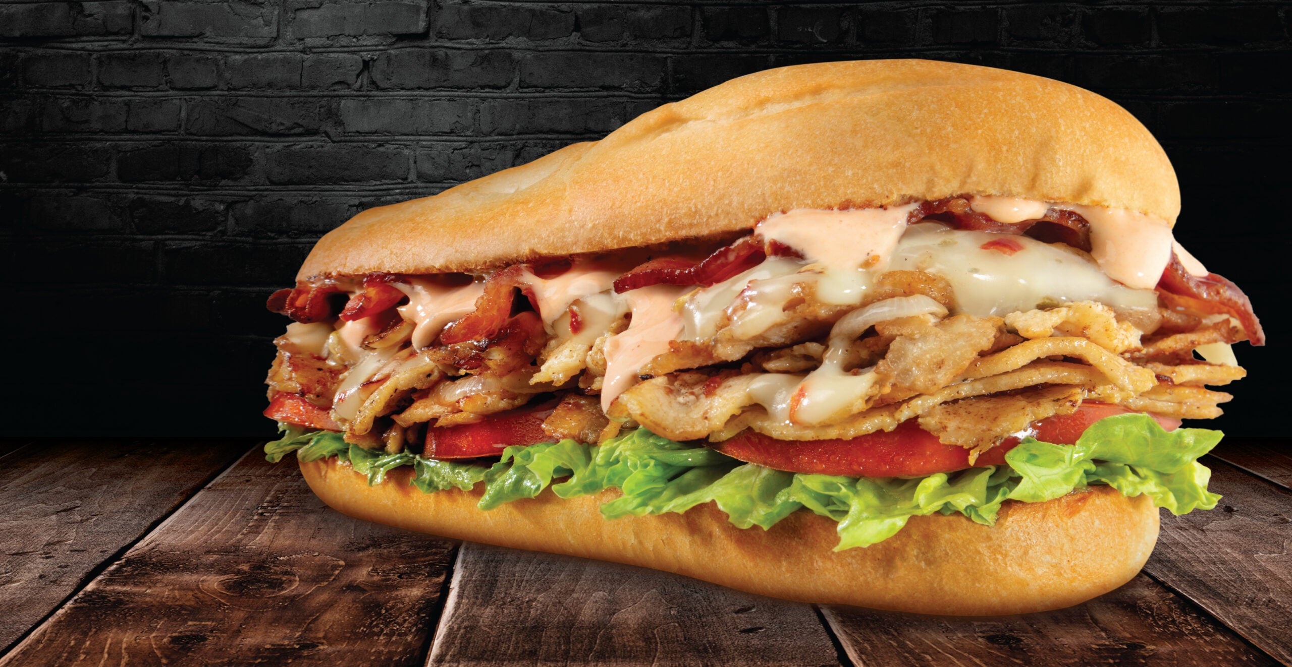 The Bacon Chipotle Cheesesteak from Charleys on a wooden table.