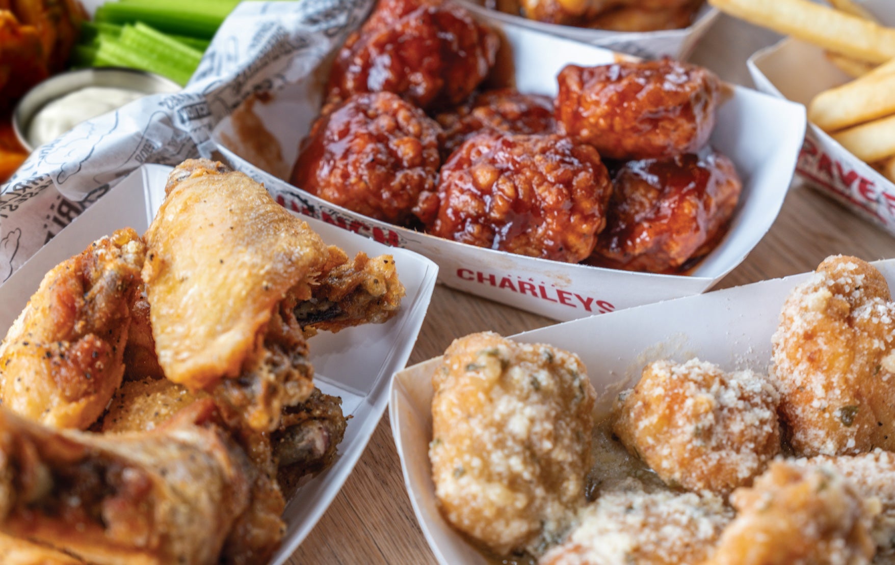 A spread of classic and boneless wings from Charleys Cheesesteaks and Wings on a table with celery.